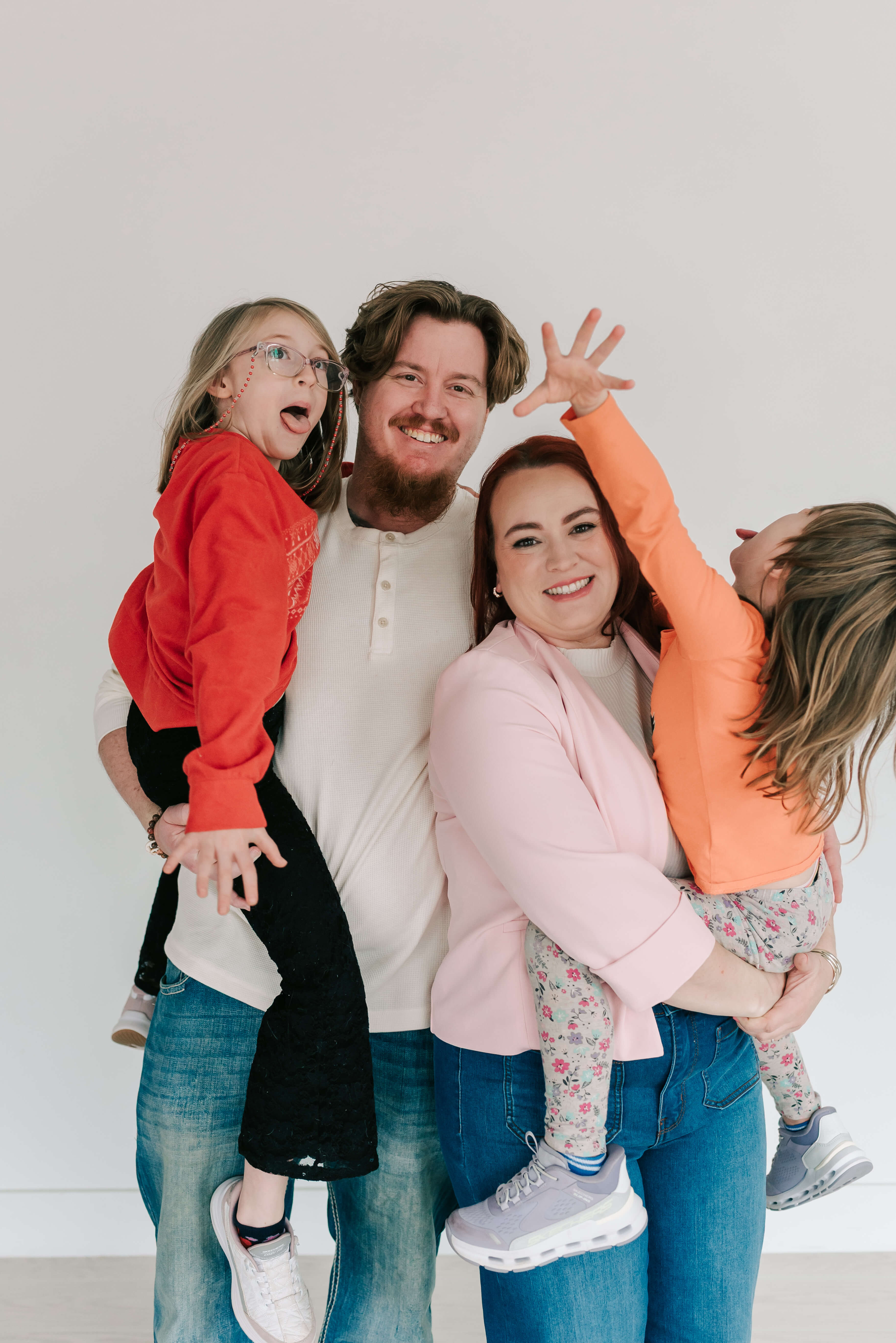 Playful family portrait of Berkeley County VW bookkeeper Jamie, her husband, and daughters waving and laughing joyfully.