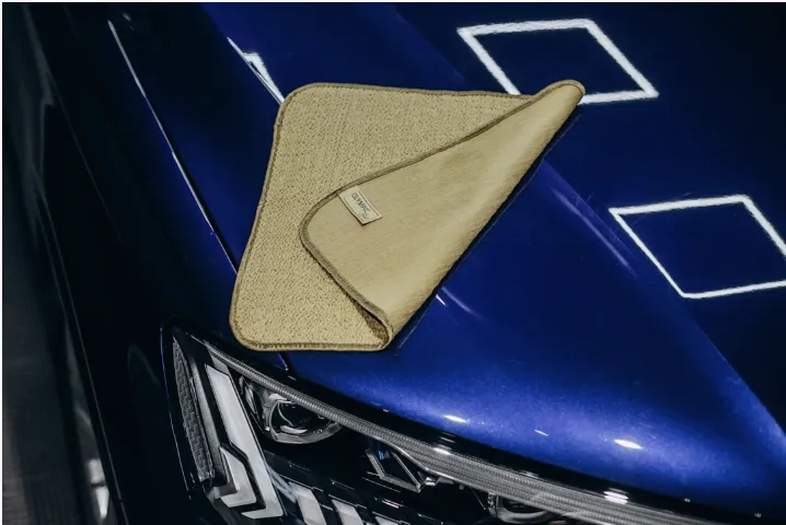 A microfiber cloth rests on a shiny blue car.