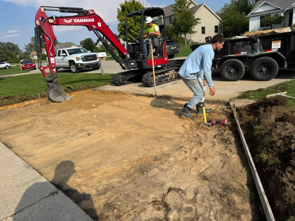 Crew preparing and grading the base for a residential concrete driveway installation in Holland, MI.