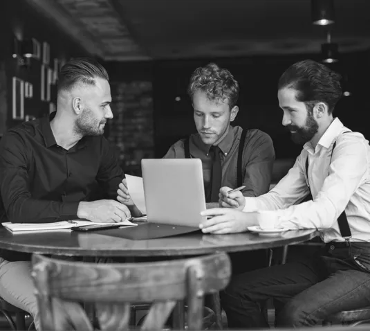 Business team discussing strategy around a laptop in a meeting