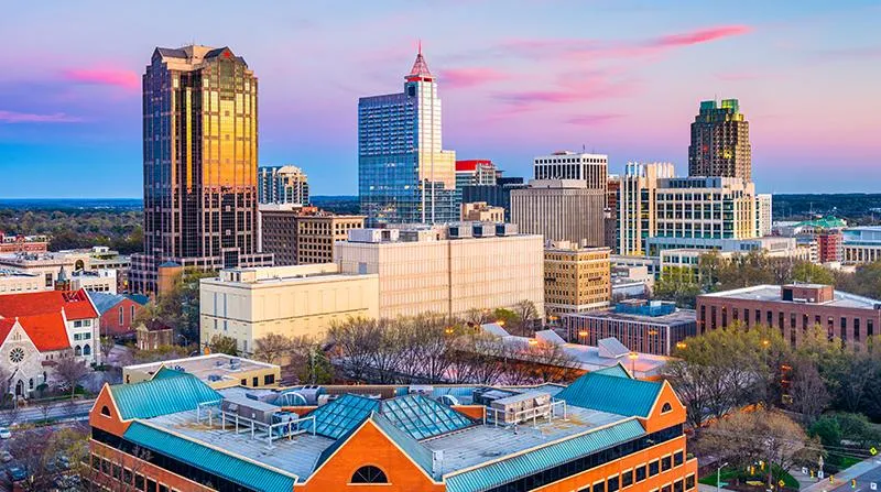 Downtown Raleigh, NC skyline at sunset featuring modern high-rise buildings and historic architecture, representing the service area of Quick Tow Towing.