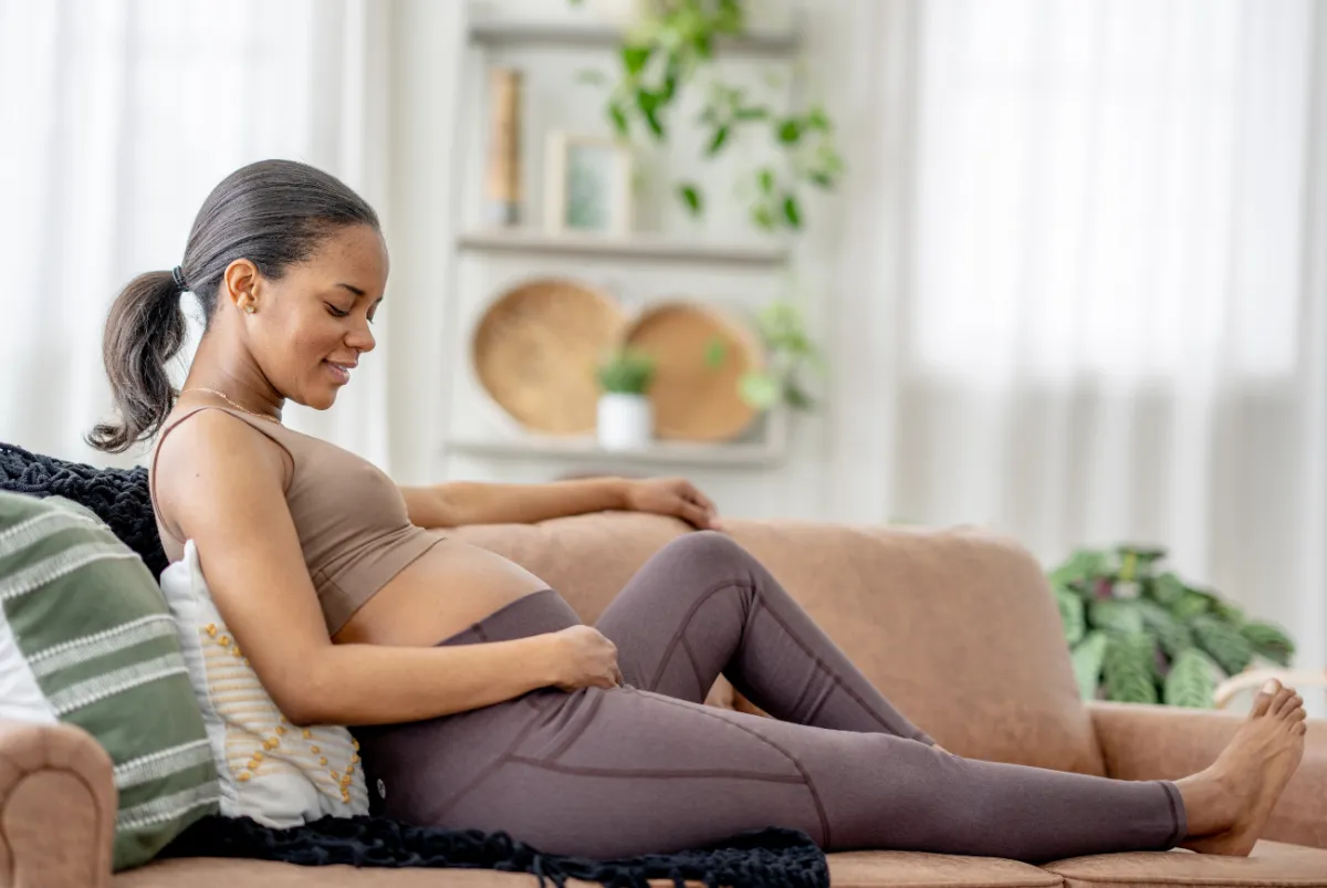 Pregnant woman relaxing on couch, representing new and expecting parents.