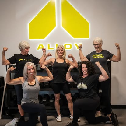 Certified personal trainers at Alloy Personal Training Kaysville posing in a small group strength training studio designed for adults over 40.