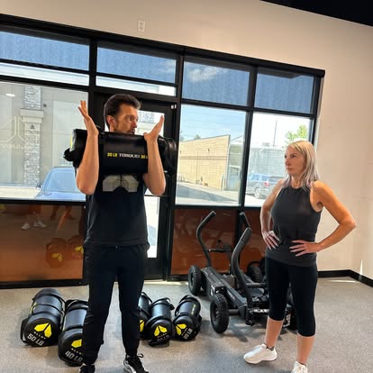 Personal trainer coaching a woman performing a kettlebell squat during functional strength training at Alloy Personal Training Kaysville.