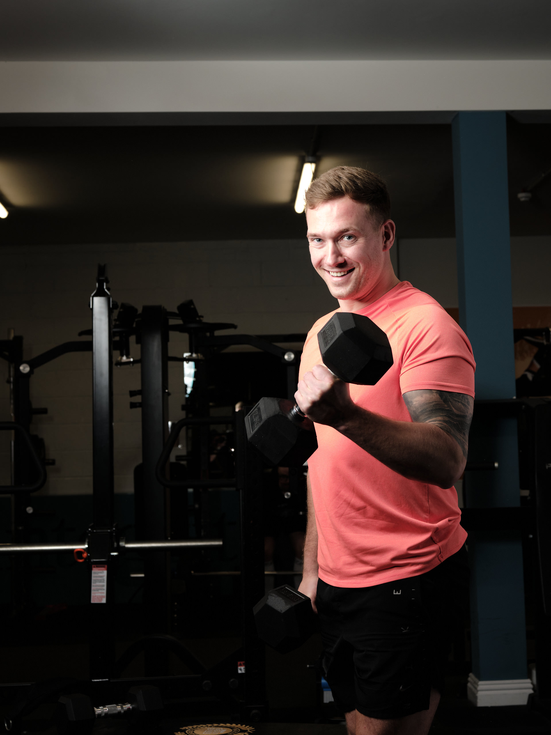 person in gray shirt holding black dumbbell