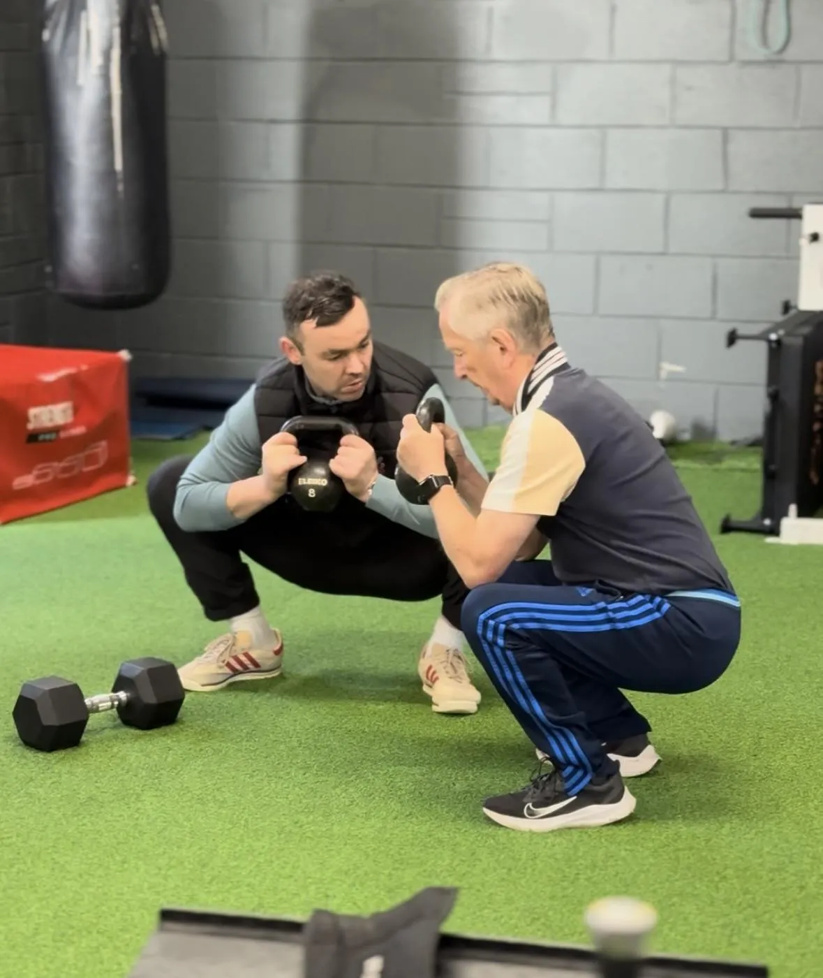 person in gray shirt holding black dumbbell