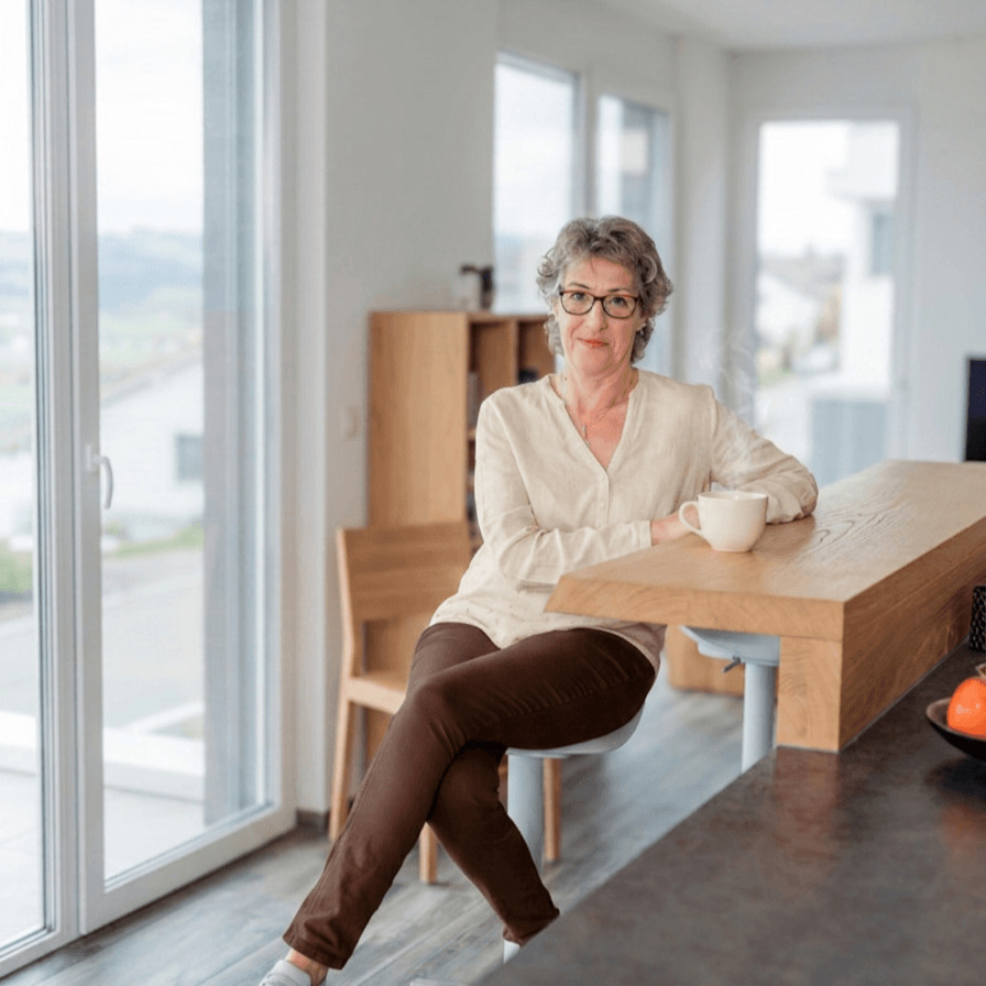 Claudia Hausheer sitzt entspannt an einem Holztisch mit Kaffeetasse