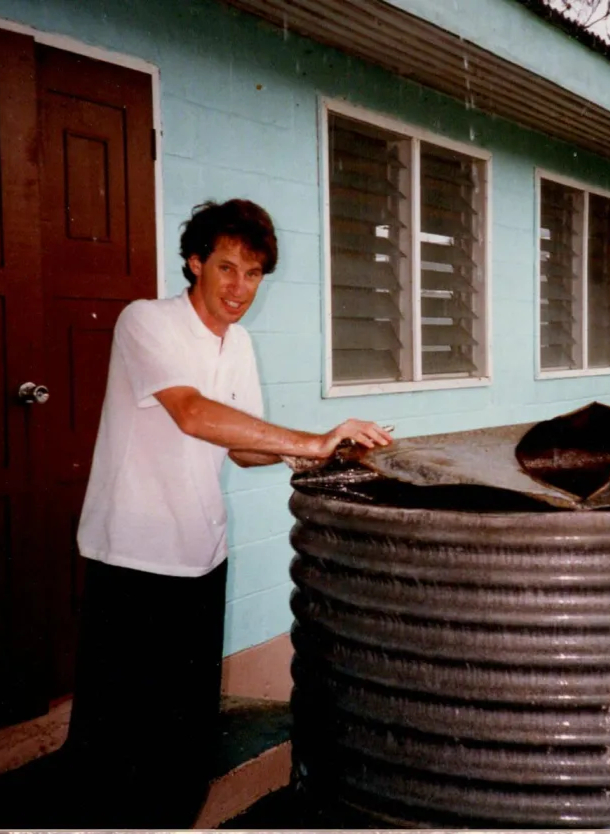 person in white shirt standing in front of a large drum of water