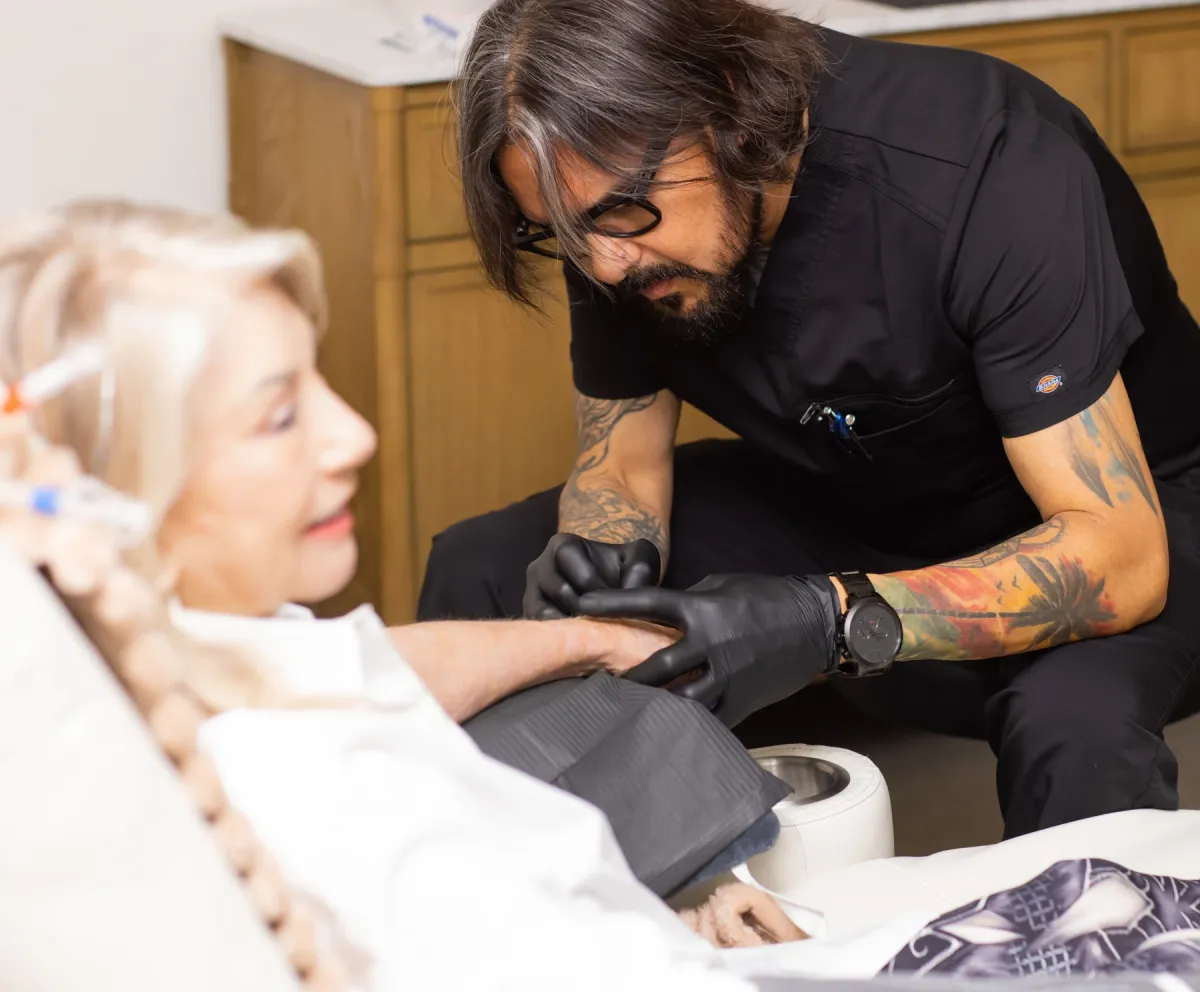 A close, unhurried moment of care beside a reclining person