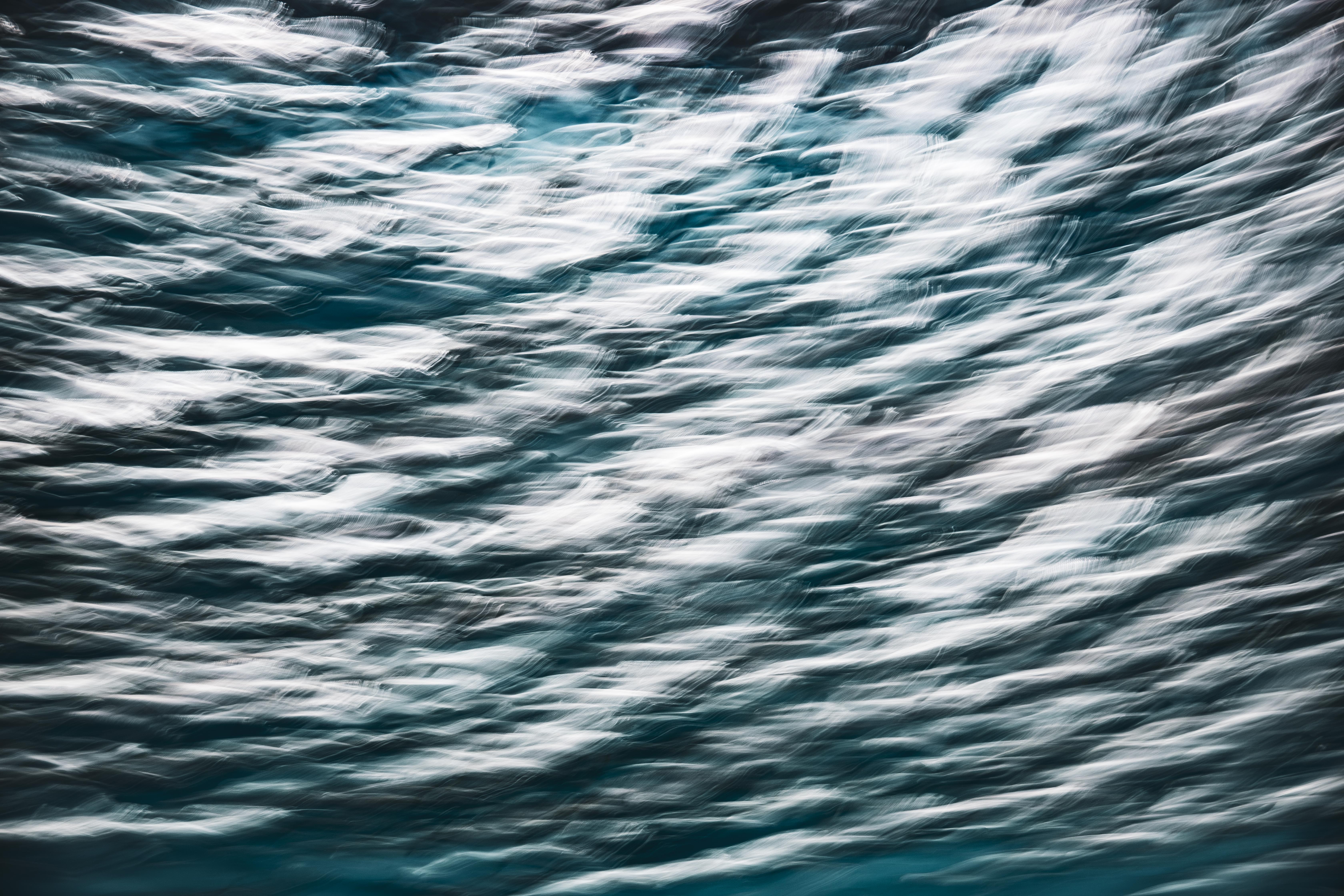 Long exposure fine art photograph at Monterey Bay Aquarium, gold light threading through a darker current of moving fish, by fine art photographer Angie Harker