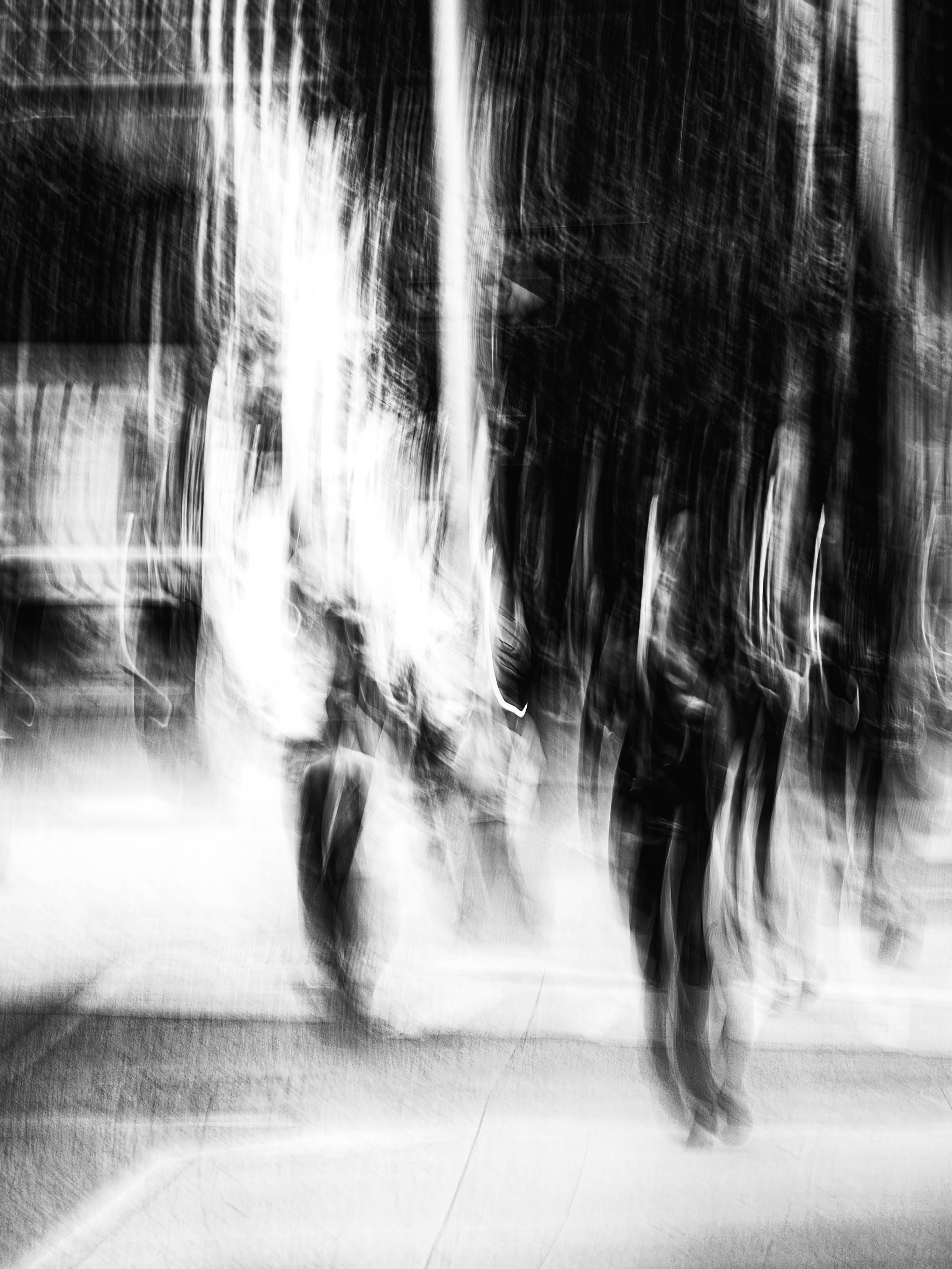 Dramatic light splitting a DUMBO Brooklyn street, figures crossing at an intersection caught between deep shadow and illuminated pavement, monochrome ICM fine art photograph by Angie Harker
