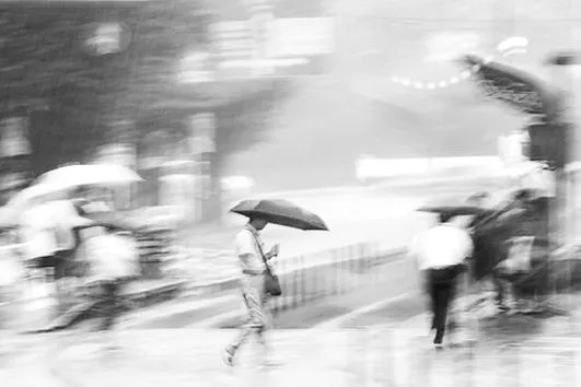A solitary man crossing calmly through a rain-soaked Kumamoto street while figures sprint for shelter around him, monochrome ICM fine art photograph by Angie Harker