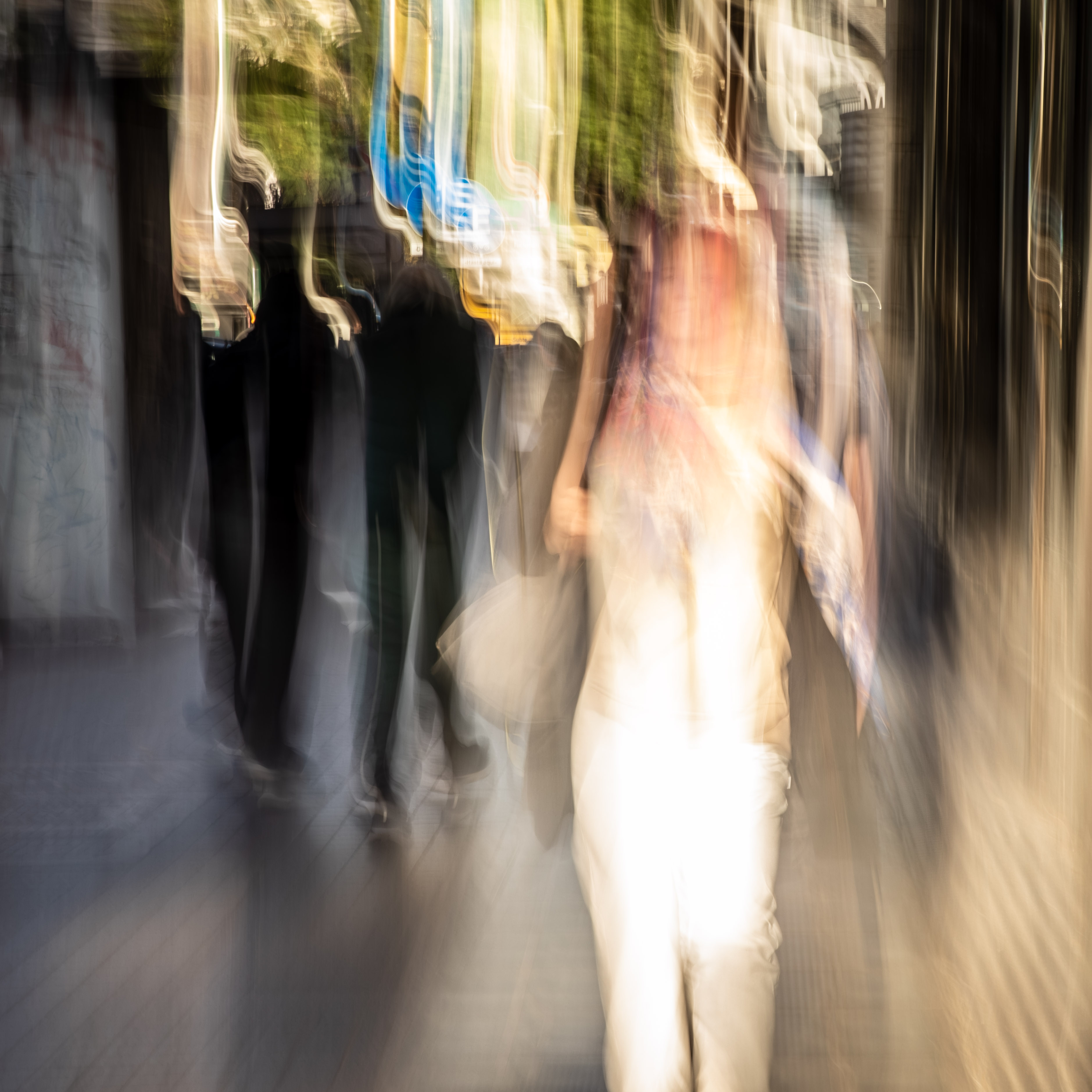 Long exposure ICM photograph of figures stretching and dissolving along a Buenos Aires street at dusk, one presence glowing mid-transition, by fine art photographer Angie Harker