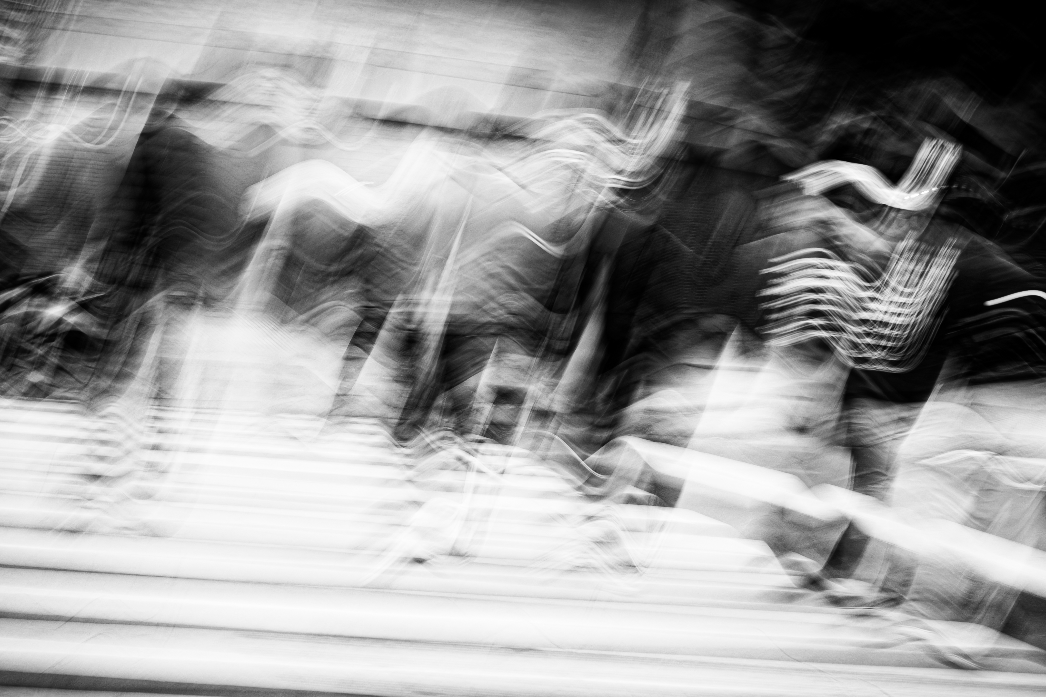 Ghosted figures and sinuous light trails moving through the Buenos Aires pedestrian zone, architecture bleeding through the upper register, baldosas striping the lower frame, tilted monochrome ICM fine art photograph by Angie Harker