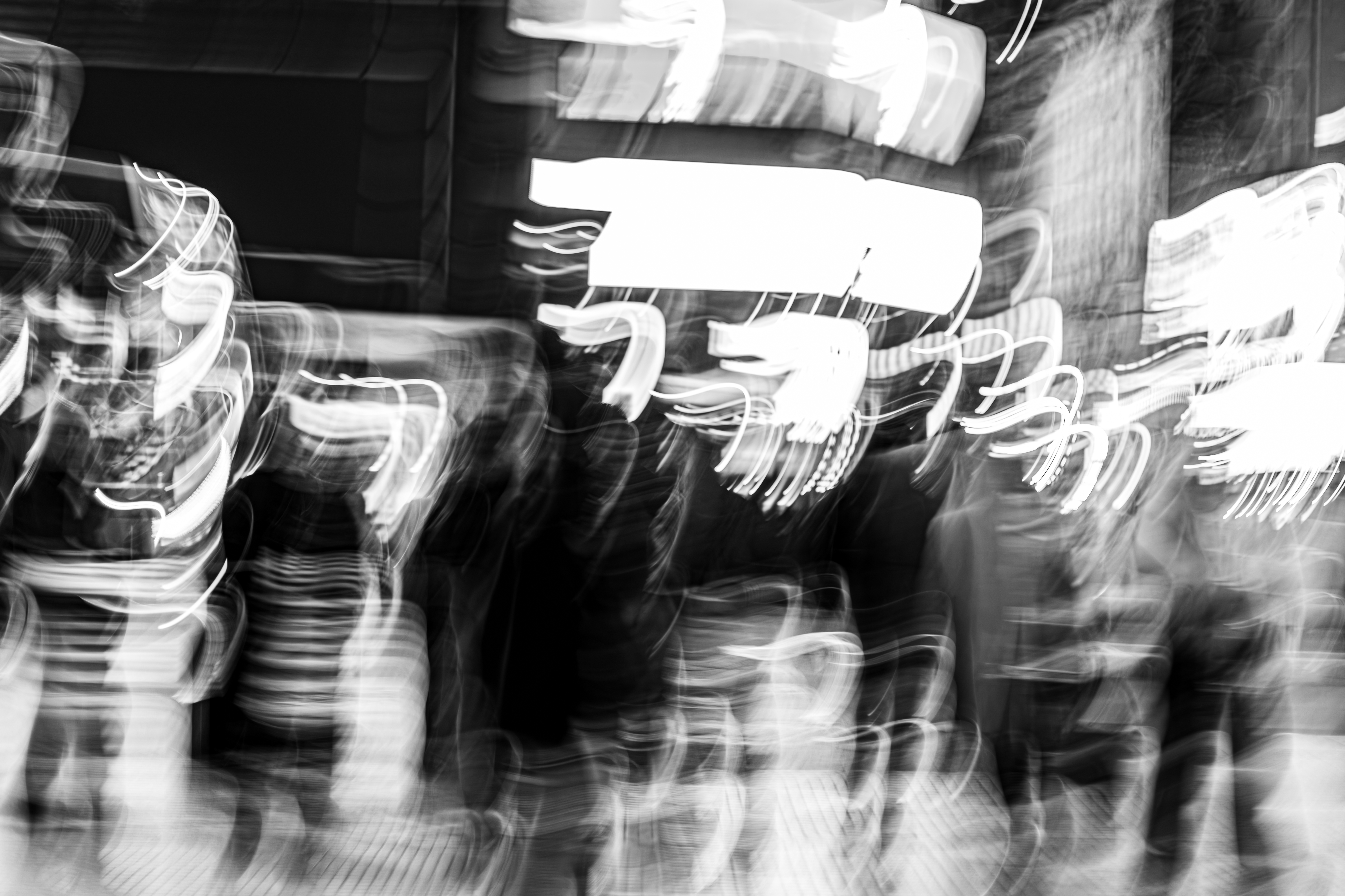 Neon light tracing sinuous cursive arcs across ghosted figures waiting to cross at a Buenos Aires intersection at night, crosswalk geometry curling through the frame, monochrome ICM fine art photograph by Angie Harker