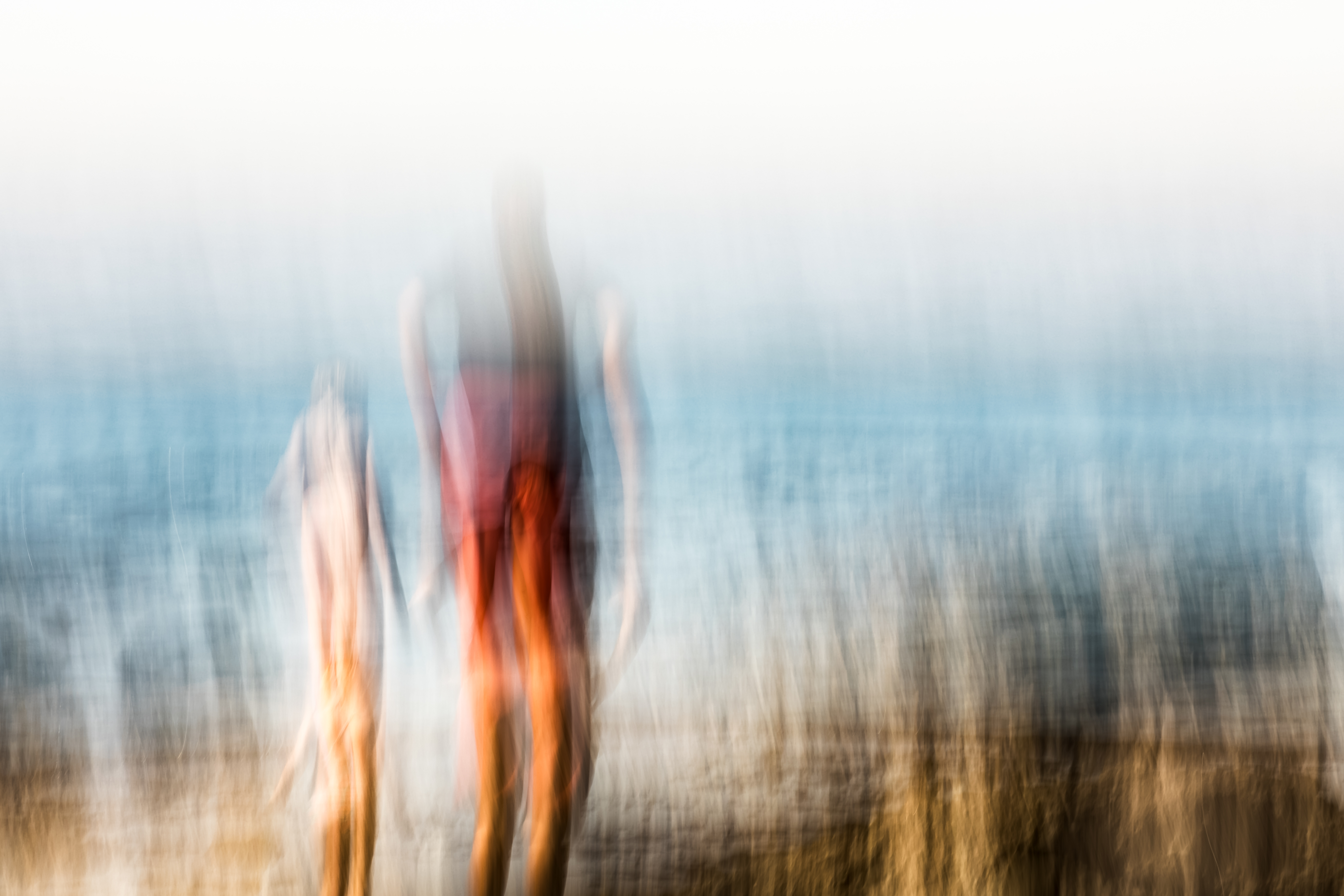 A parent and child elongated into luminous vertical silhouettes through intentional camera movement at the Aliso Creek Beach tide pools, warm color palette, ICM fine art photograph by Angie Harker