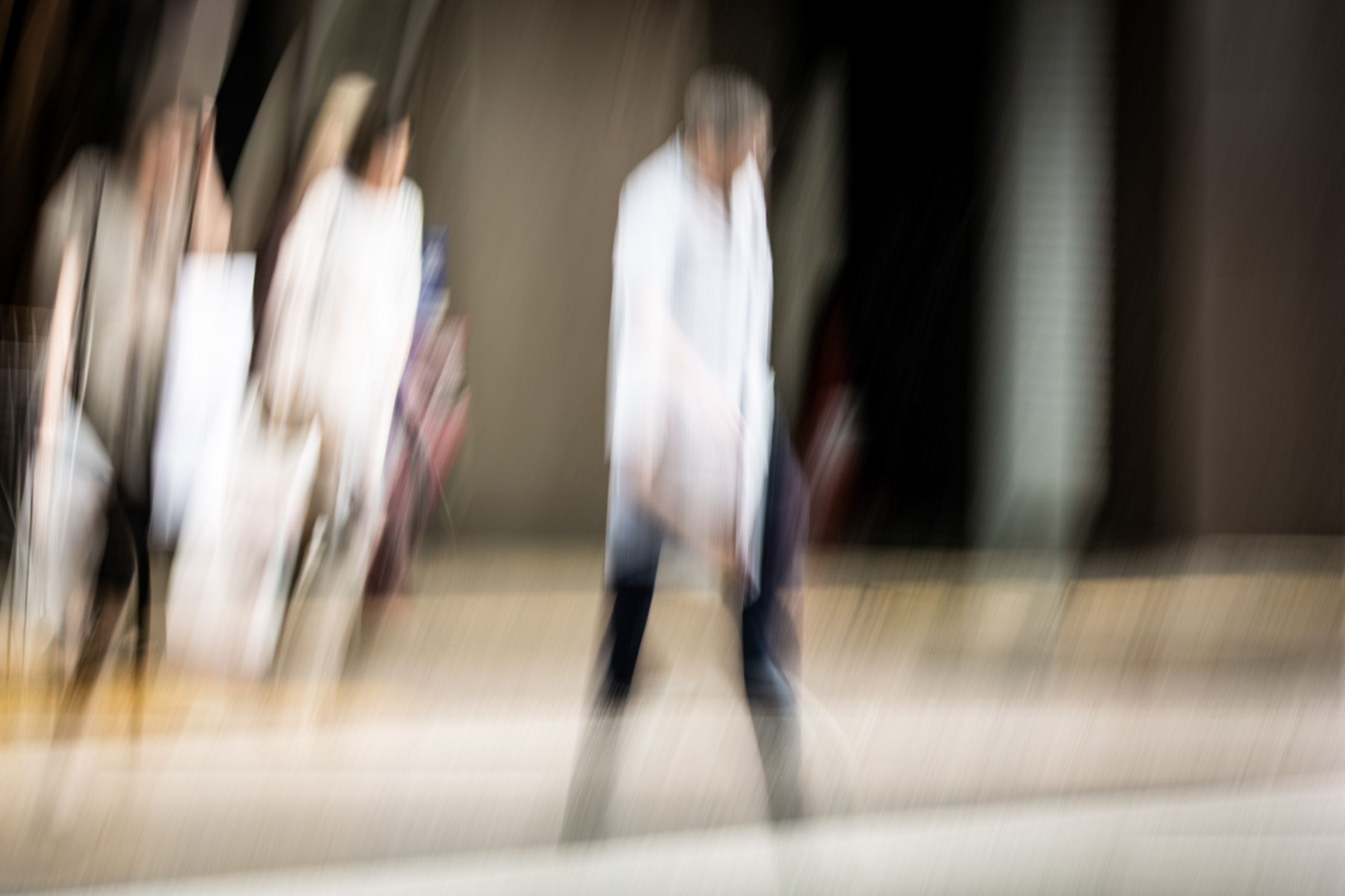 Long exposure ICM photograph of figures crossing a threshold from shelter into exposure on a Kumamoto street in tropical rain, by fine art photographer Angie Harker