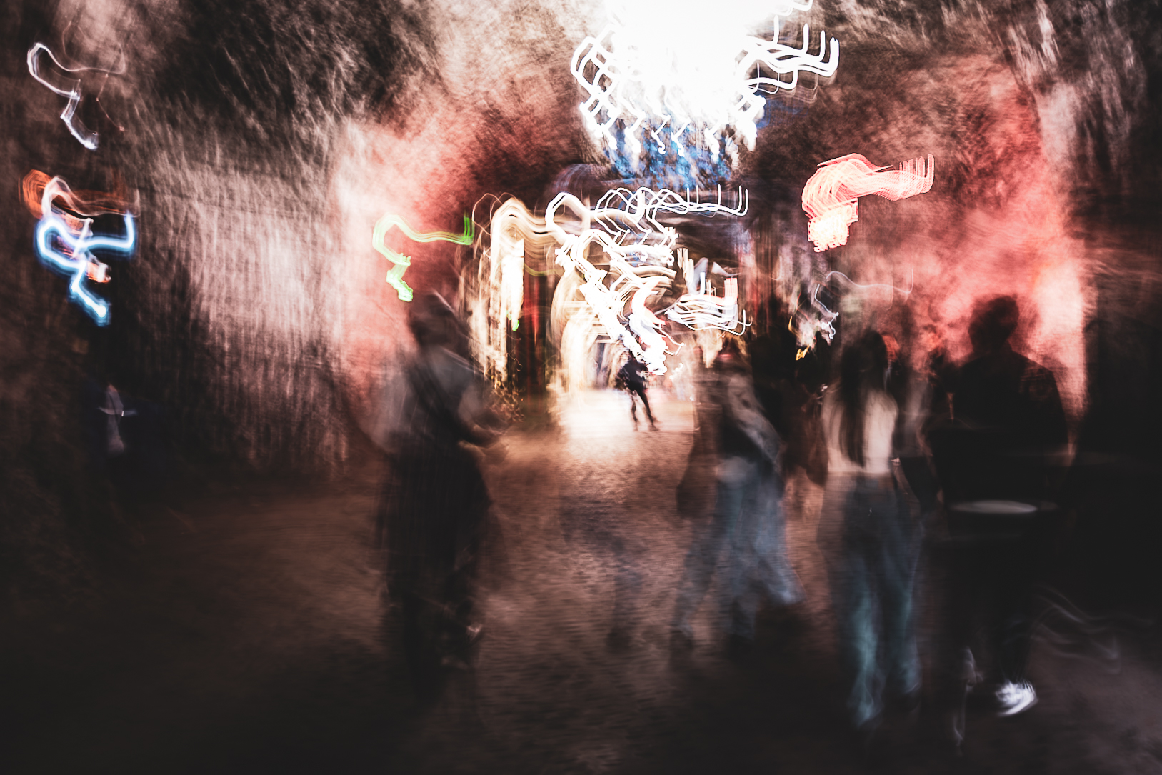 Long exposure ICM photograph of figures moving through the Salt Cathedral of Zipaquirá, Colombia, one still presence holding amid motion and dissolving color, by fine art photographer Angie Harker