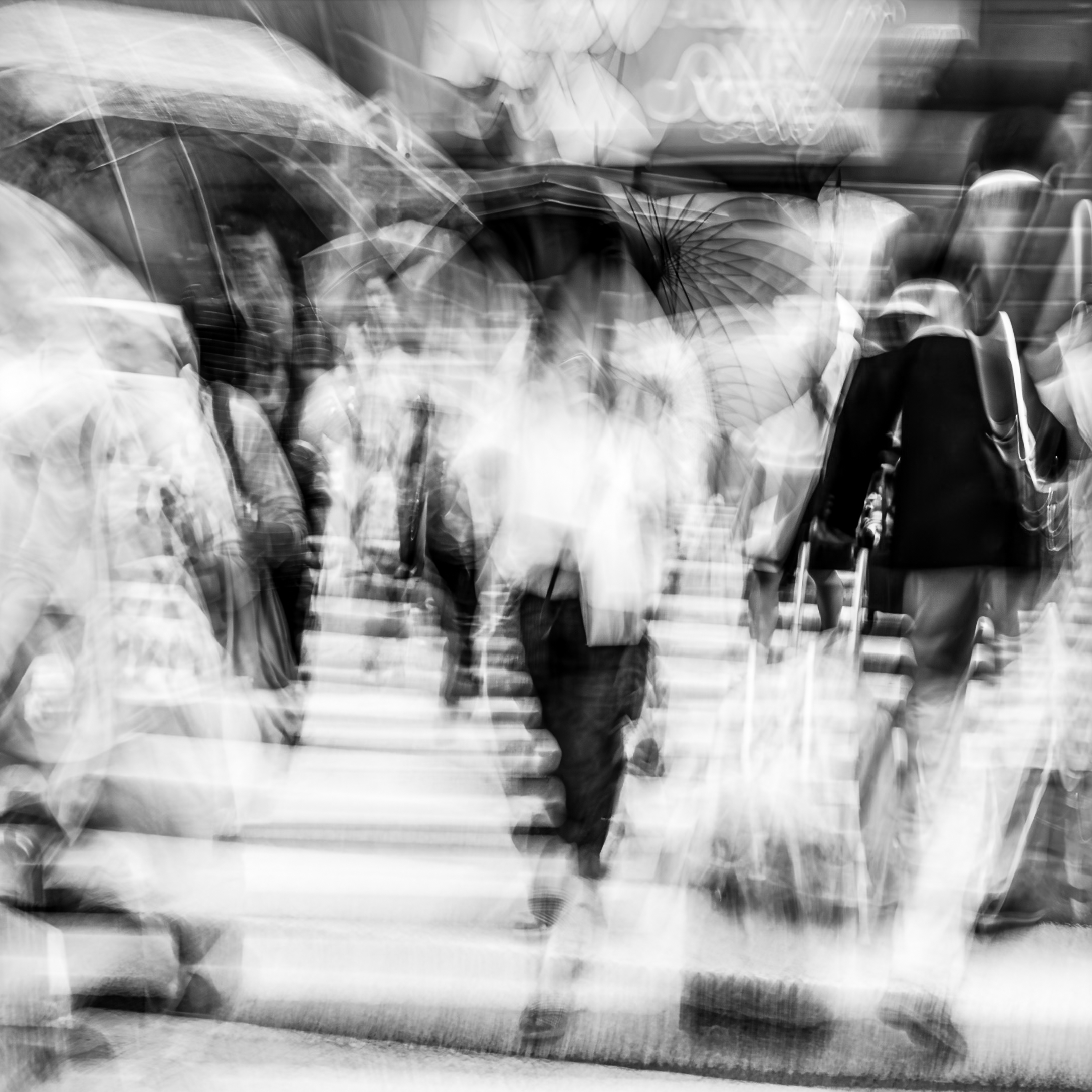 Figures moving through a rain-soaked Fukuoka crosswalk, umbrellas layering across the upper frame, crosswalk stripes raking the lower register, approaching figure visible against ghosted crowd, monochrome ICM fine art photograph by Angie Harker