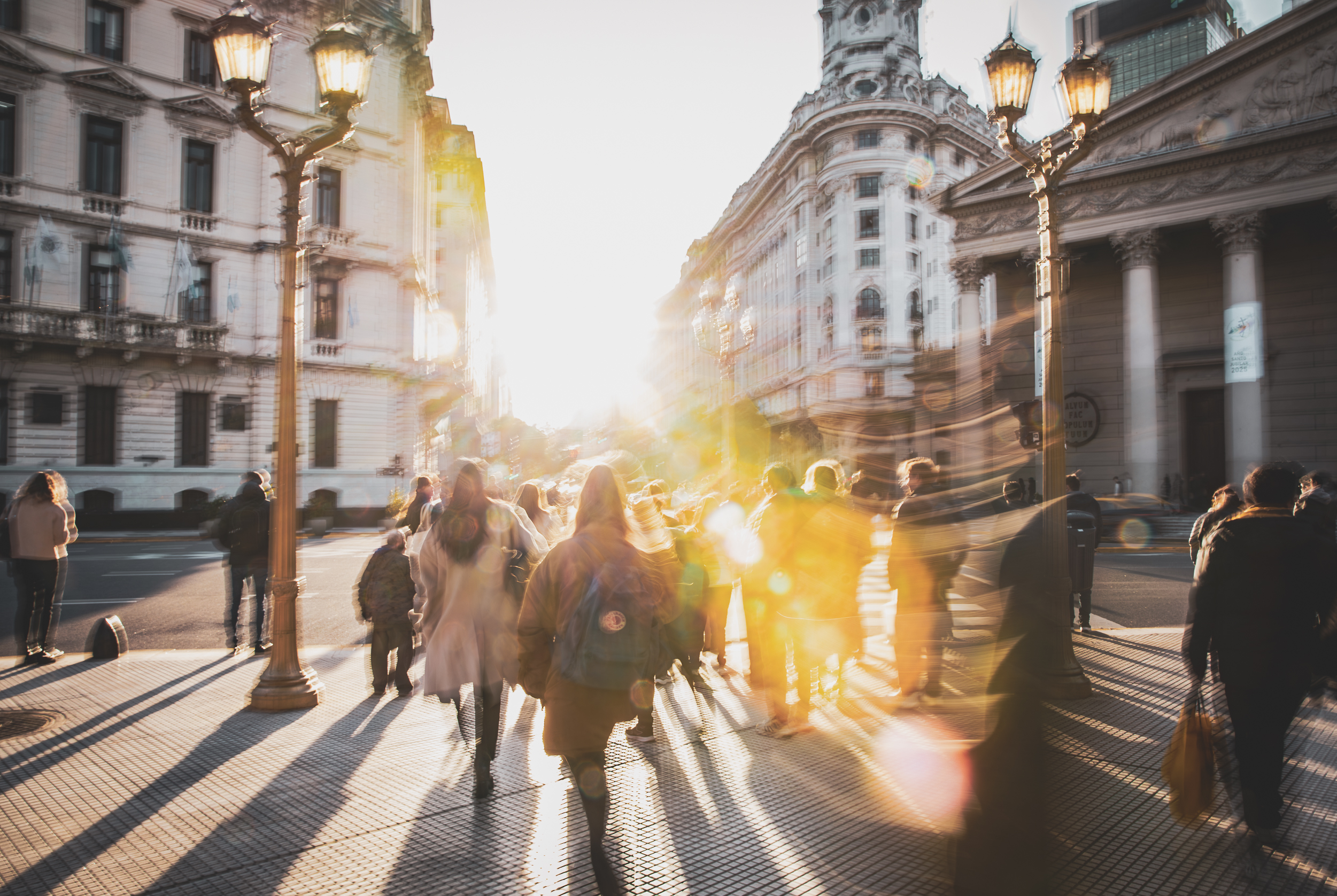Long exposure ICM photograph of figures layered in golden light at winter dusk in Buenos Aires, shadows stretching long across cobblestones, by fine art photographer Angie Harker