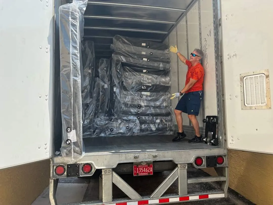 A truckload of mattresses with someone standing in the truck ready to unload