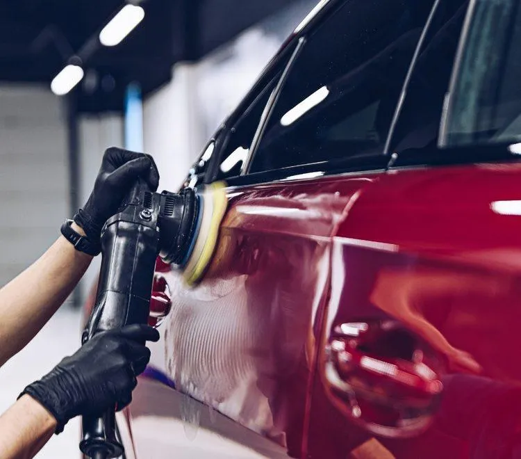 Detailing technician polishing vehicle paint to restore shine