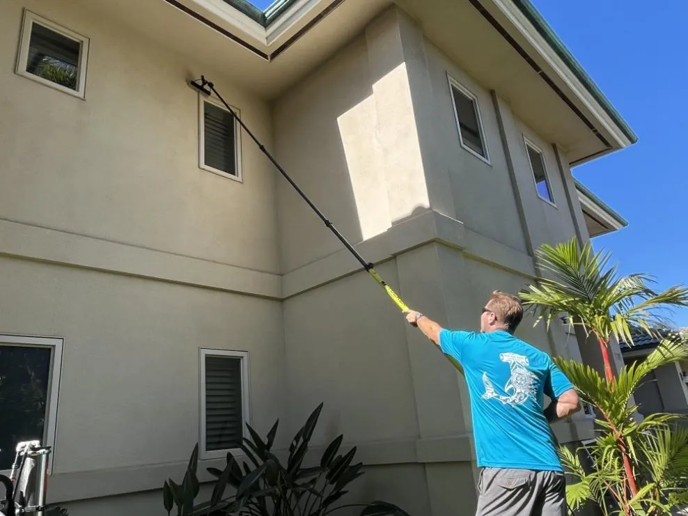 Technician squeegeeing a large window with ocean view