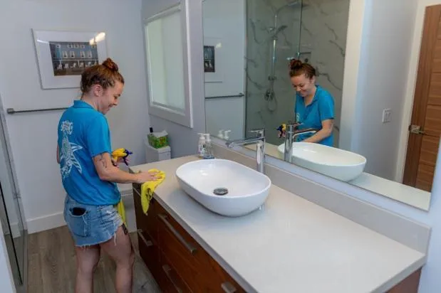 Housekeeper cleaning bathroom countertop and sink