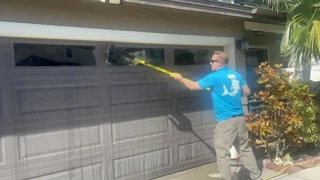 Technician cleaning a large window with a squeegee