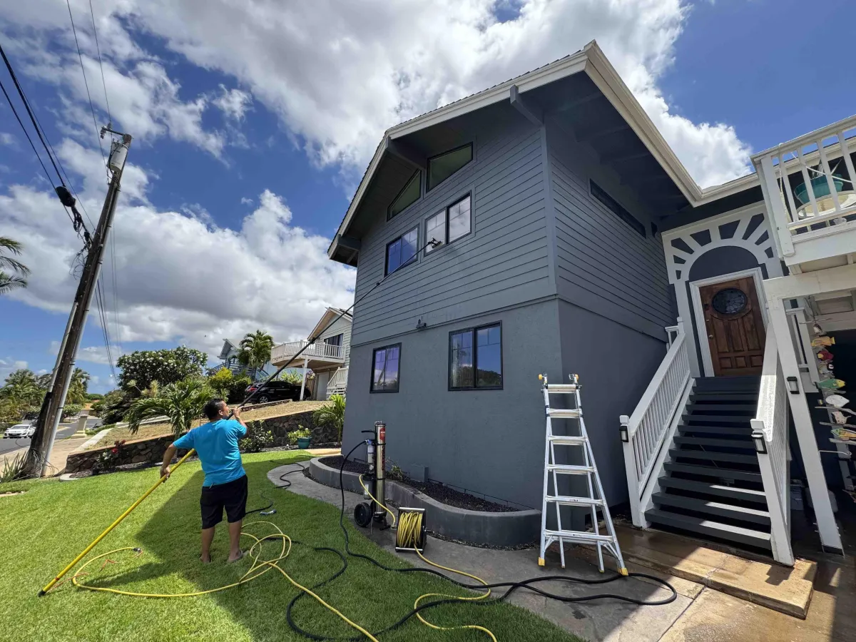 Window cleaner on ladder washing upper story windows