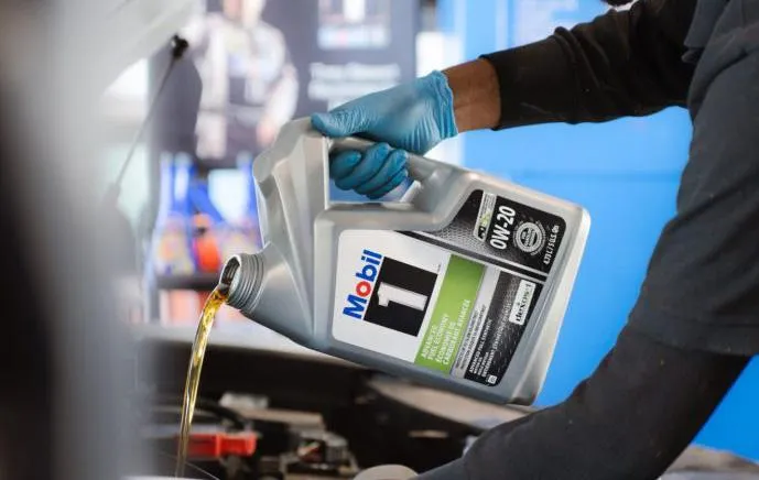 Mechanic performing a Mobil 1 synthetic oil change at United Oil Change Club in Garden City, Michigan, pouring high-performance oil into a vehicle engine for premium protection.
