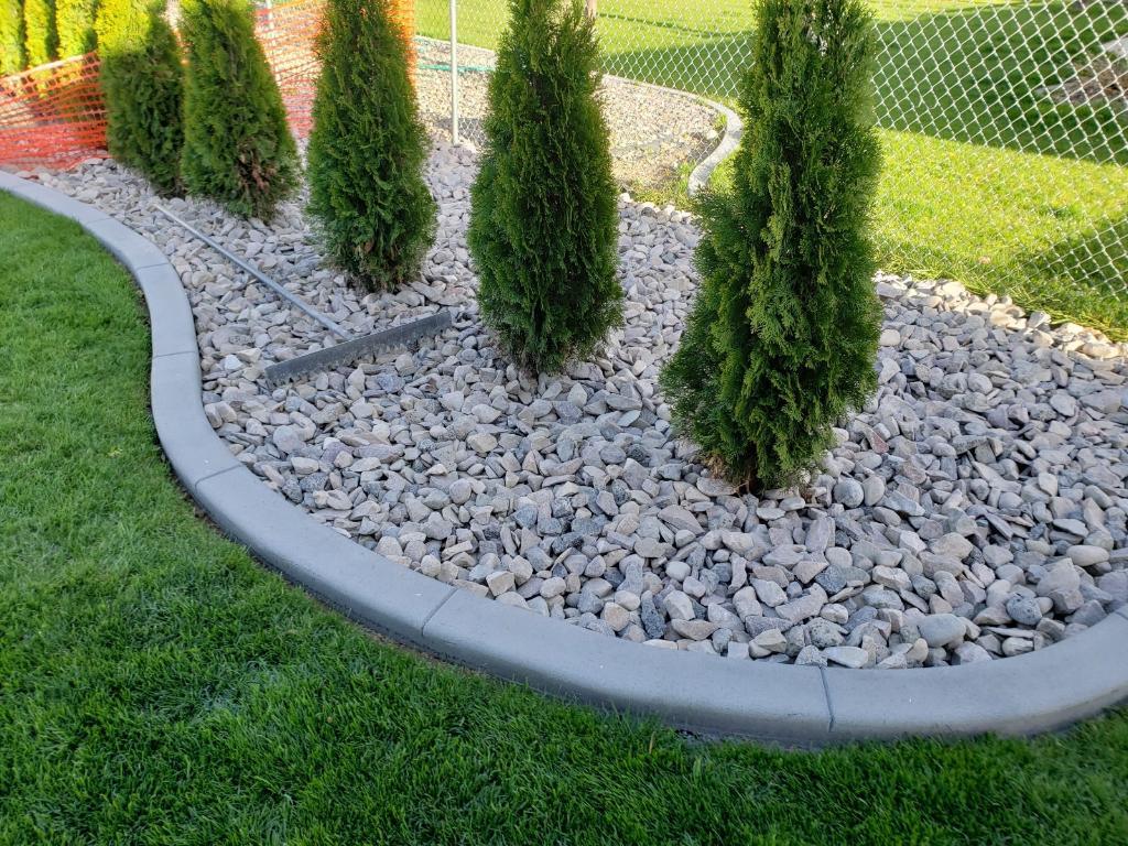 Concrete curbing separating some bushes from the grass and keep the cover in.