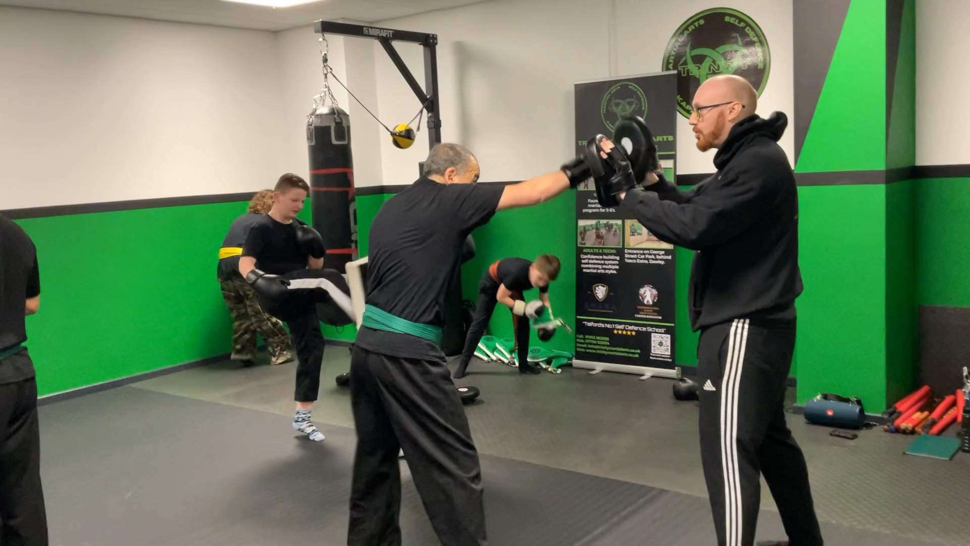 Teens and adults practising partner drills in a structured martial arts class