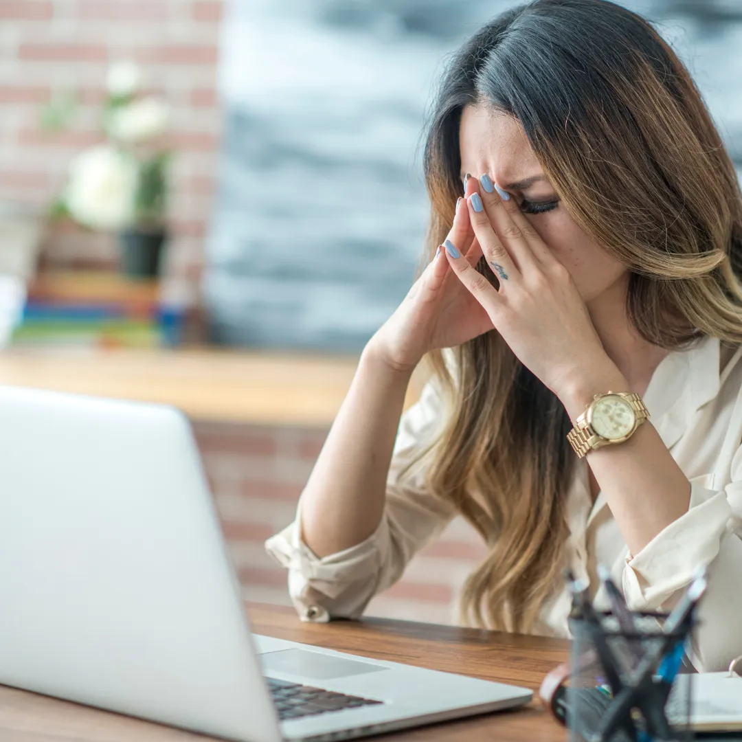 A frustrated woman sitting at her desk, overwhelmed by complicated software, finding relief as the Simple Business Suite offers her a simpler, all-in-one solution to manage her business efficiently.