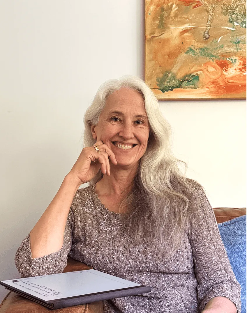Megan, a hypnotherapist and coach in Sydney, smiling on couch