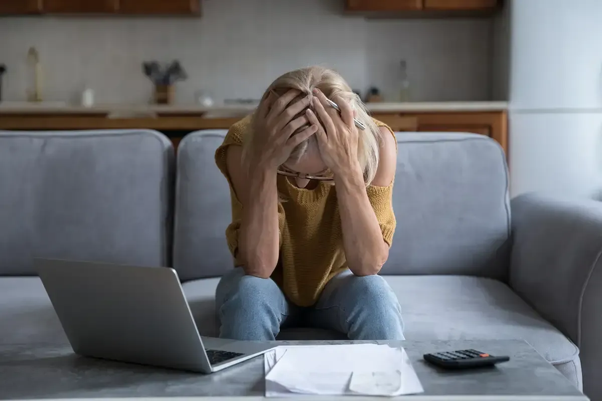 Homeowner in their mid-40s reviewing foreclosure paperwork at a kitchen table by natural window light.
