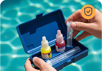 Pool water testing kit with chemical reagents and test tubes, hands holding the kit above a sparkling blue pool, symbolizing Strong Tower Pool's commitment to balanced, healthy water maintenance.