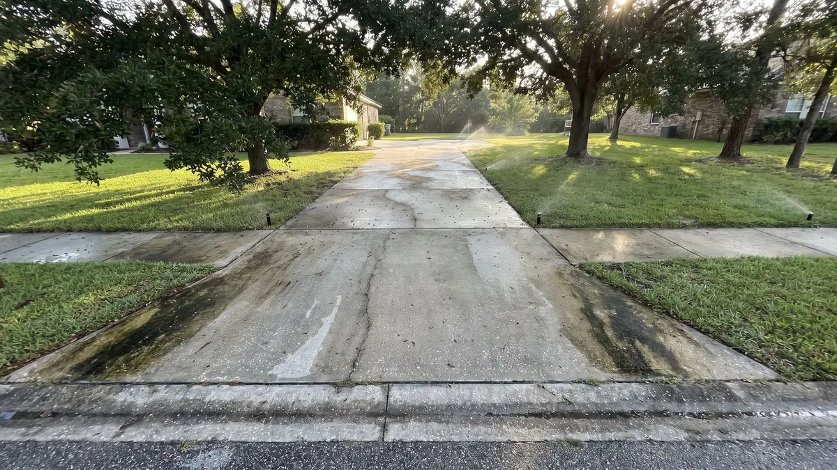 Algae-darkened driveway and sidewalk at an Aberdeen, St. Johns FL home before driveway cleaning