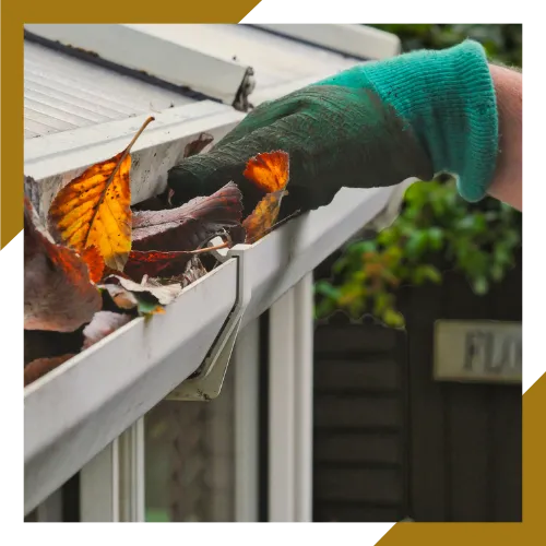Technician removing leaves and debris during clogged gutter cleaning service