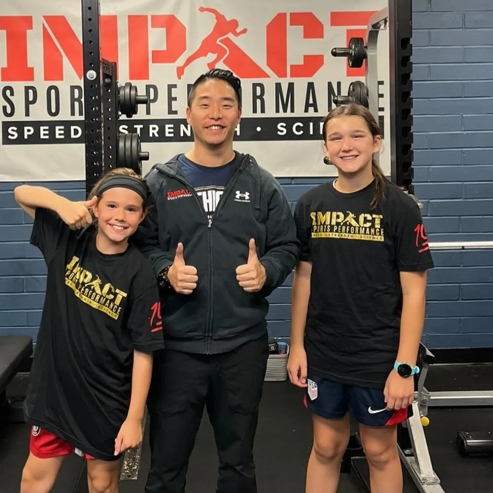 Coach and youth athlete holding Impact Sports Performance shirt after joining training program