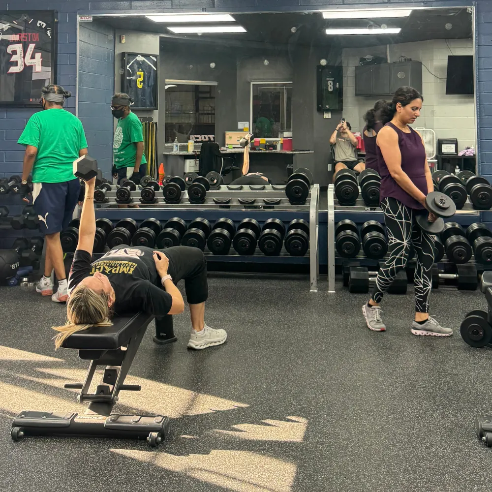 Coach leading adult small group strength training session at Impact Sports Performance