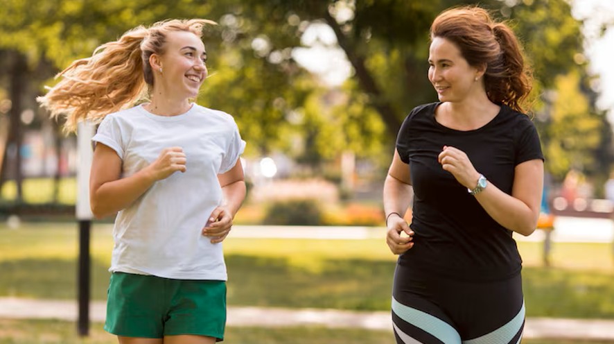 two women running and laughing together in a park, enjoying better health from a women's health acupuncture clinic in woodbury mn.