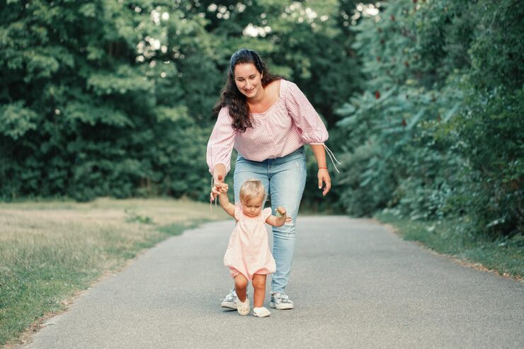 happy mother helping toddler walk in the park thanks to successful fertility acupuncture in woodbury mn.