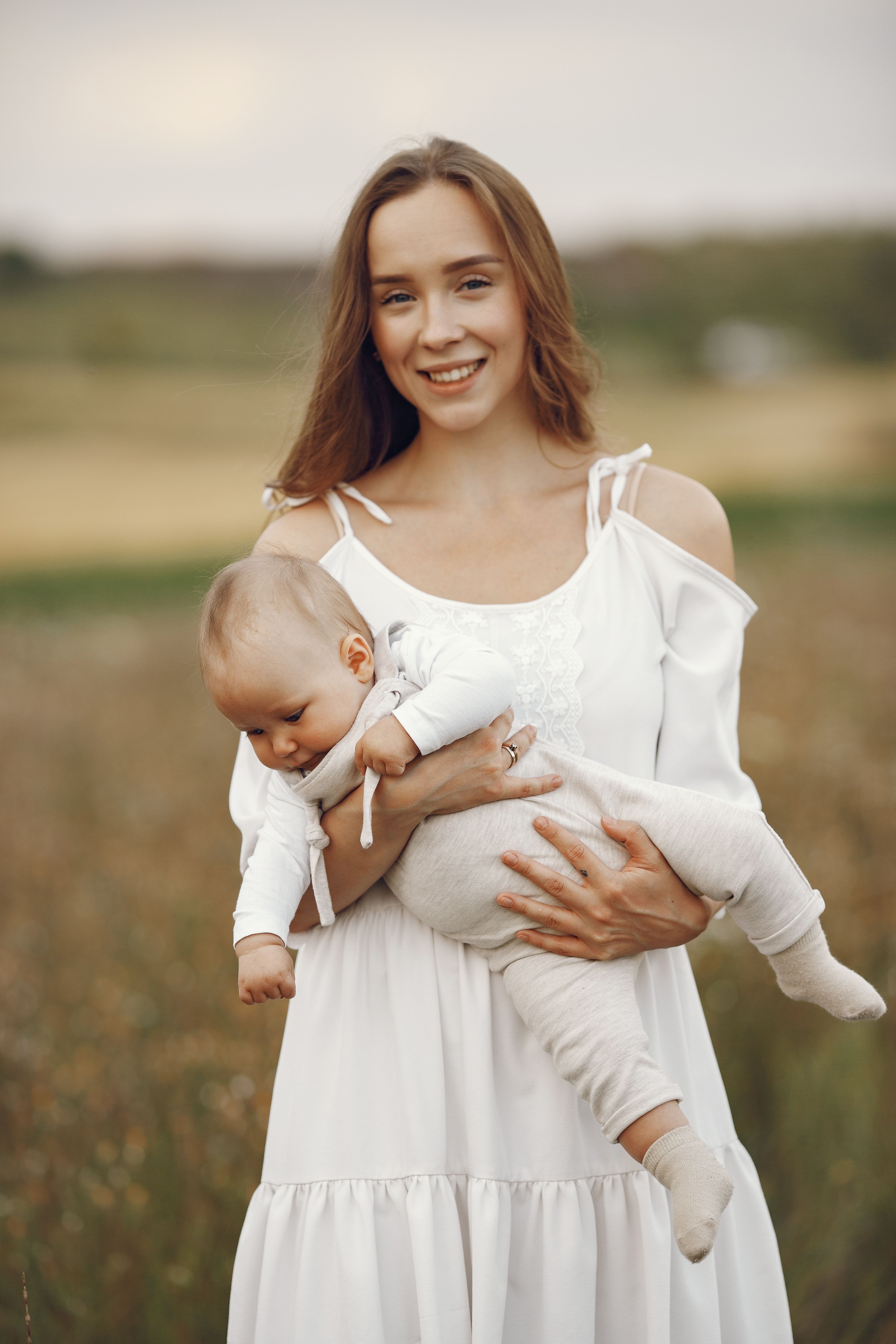 mother holding her newborn baby in a field, showing the successful outcome of treatment at a woodbury mn clinic.