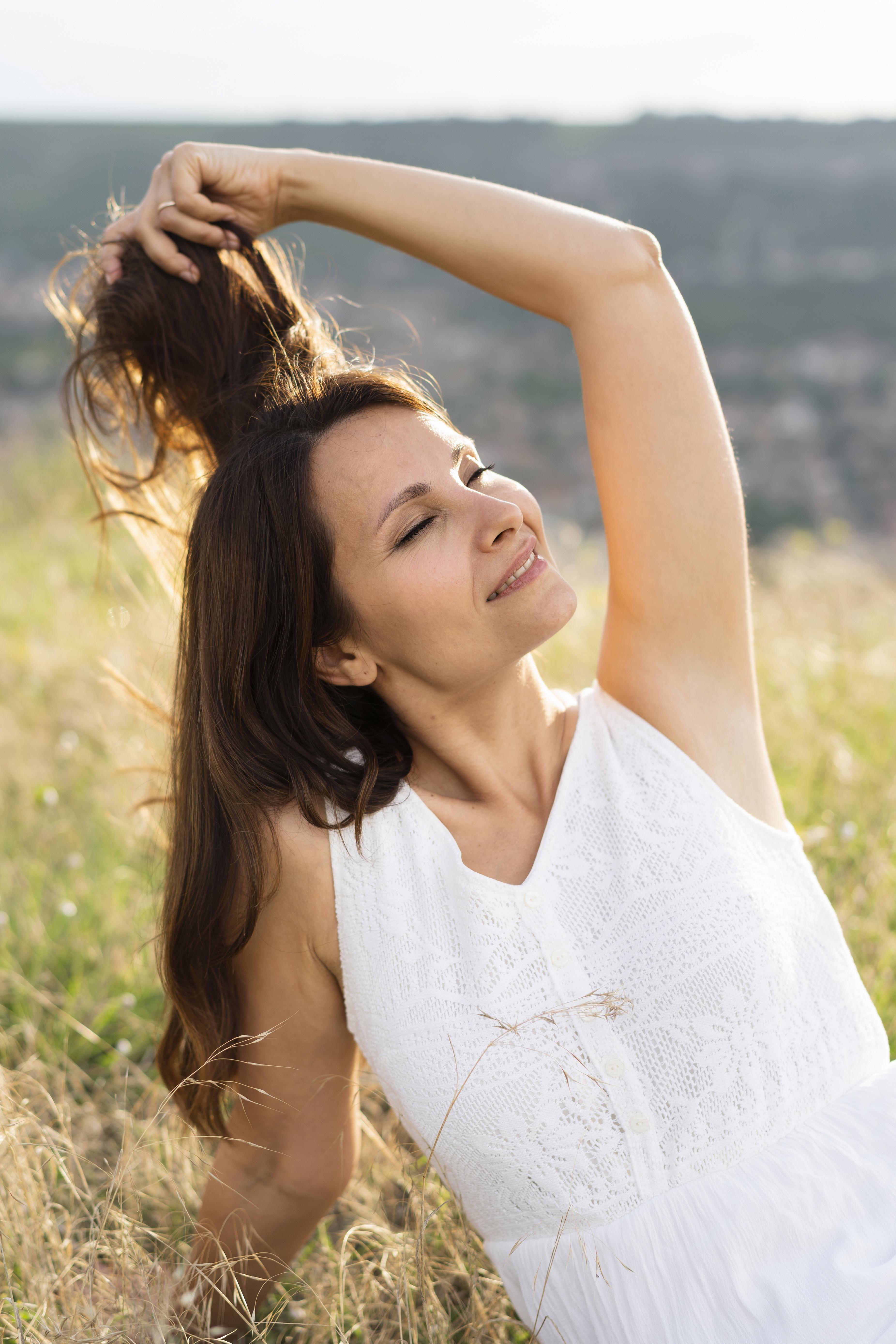woman smiling with eyes closed in a field after treatment at an acupuncture clinic in woodbury mn.
