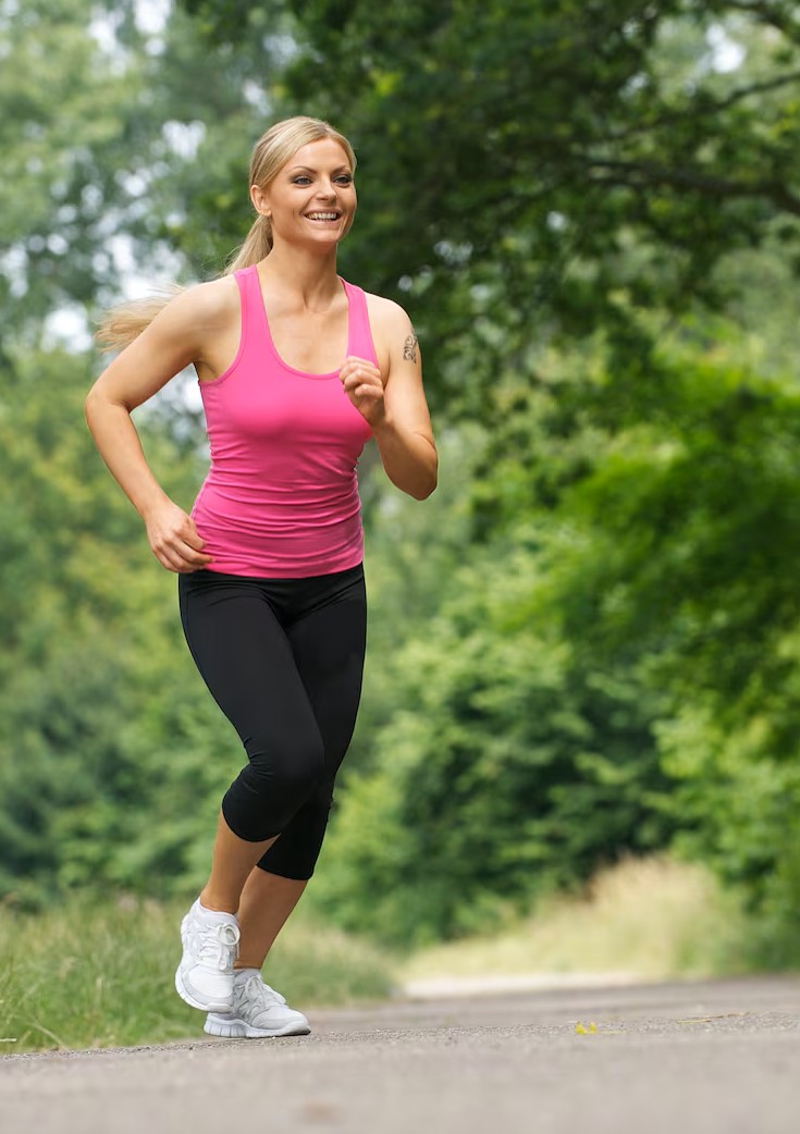 active woman jogging through a green park feeling healthy and pain free after visiting an acupuncture clinic in woodbury mn.