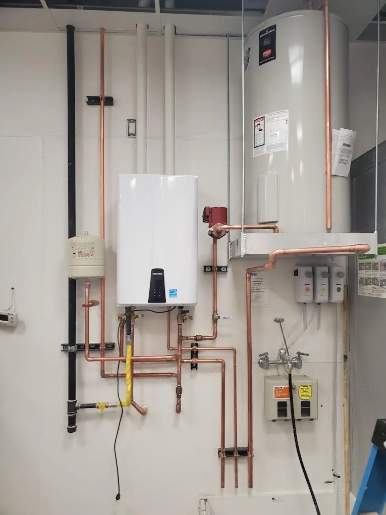 A tankless and tank water heater next to each other on the wall..