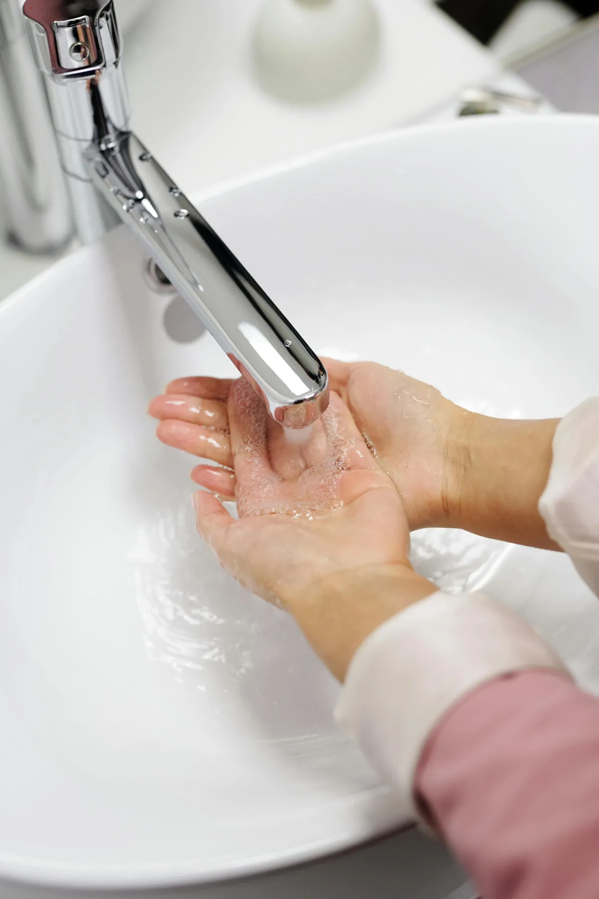 Woman washing hands in the bathroom sink.