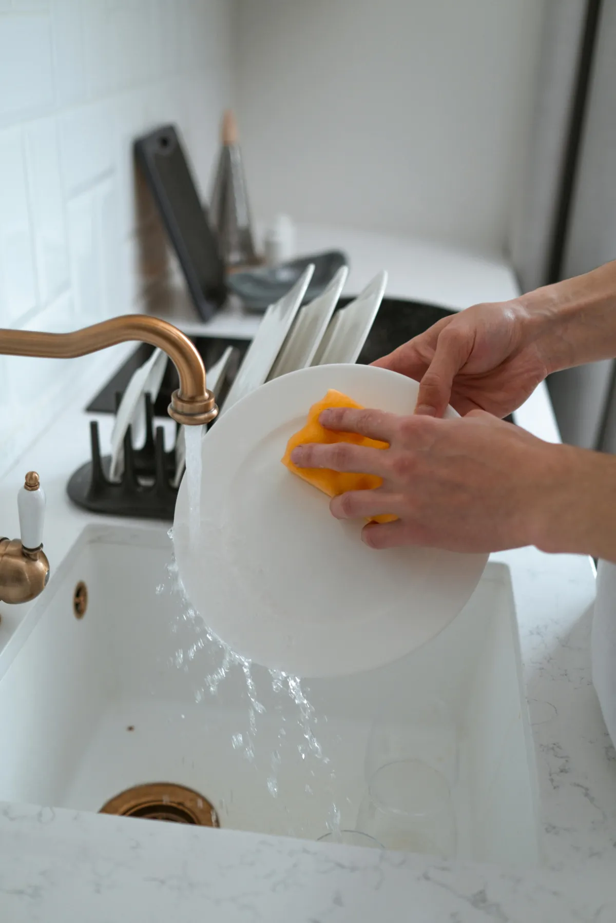 Man washing dishes in the kitchen sink.