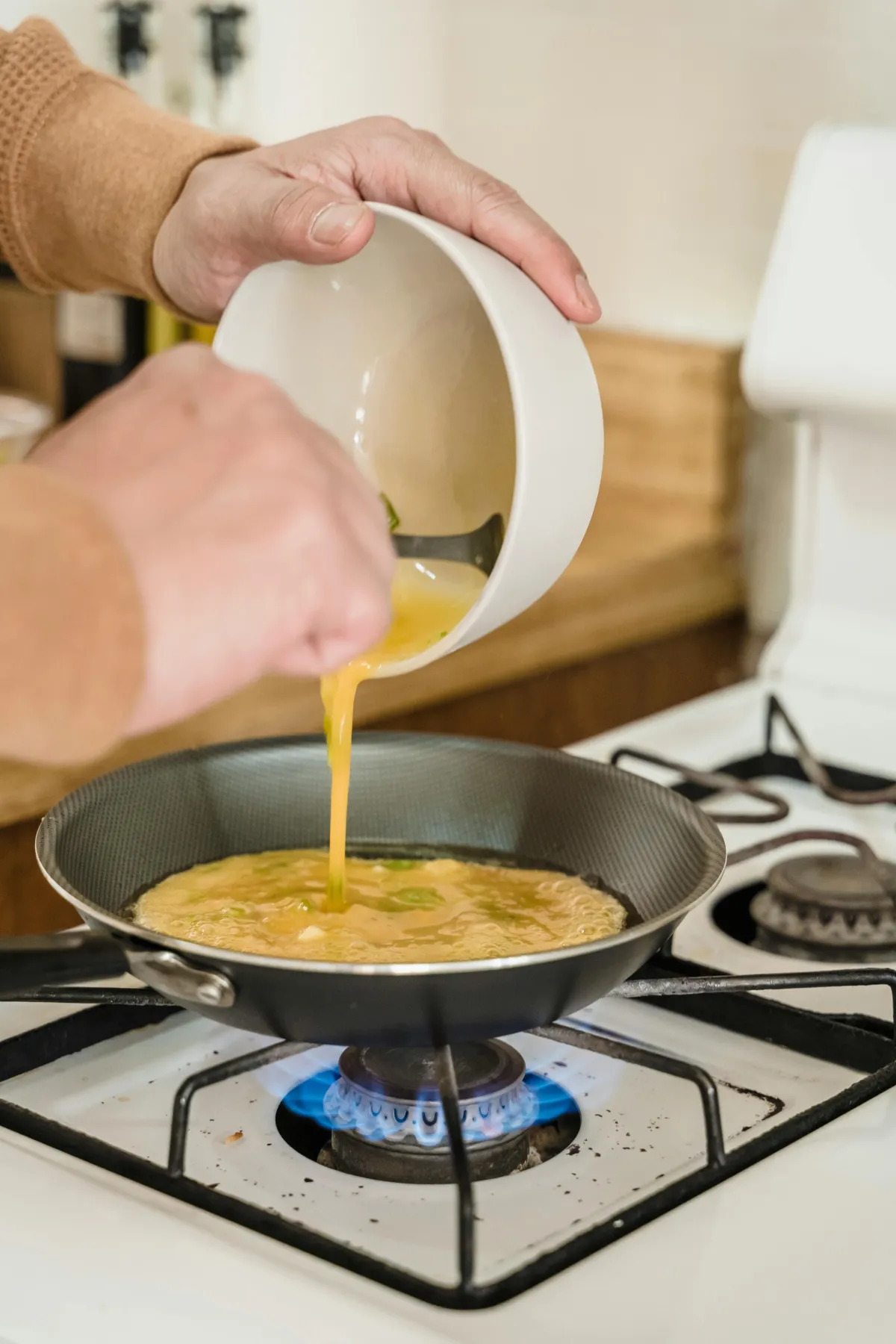 Man cooking scramble eggs over a as stove top.